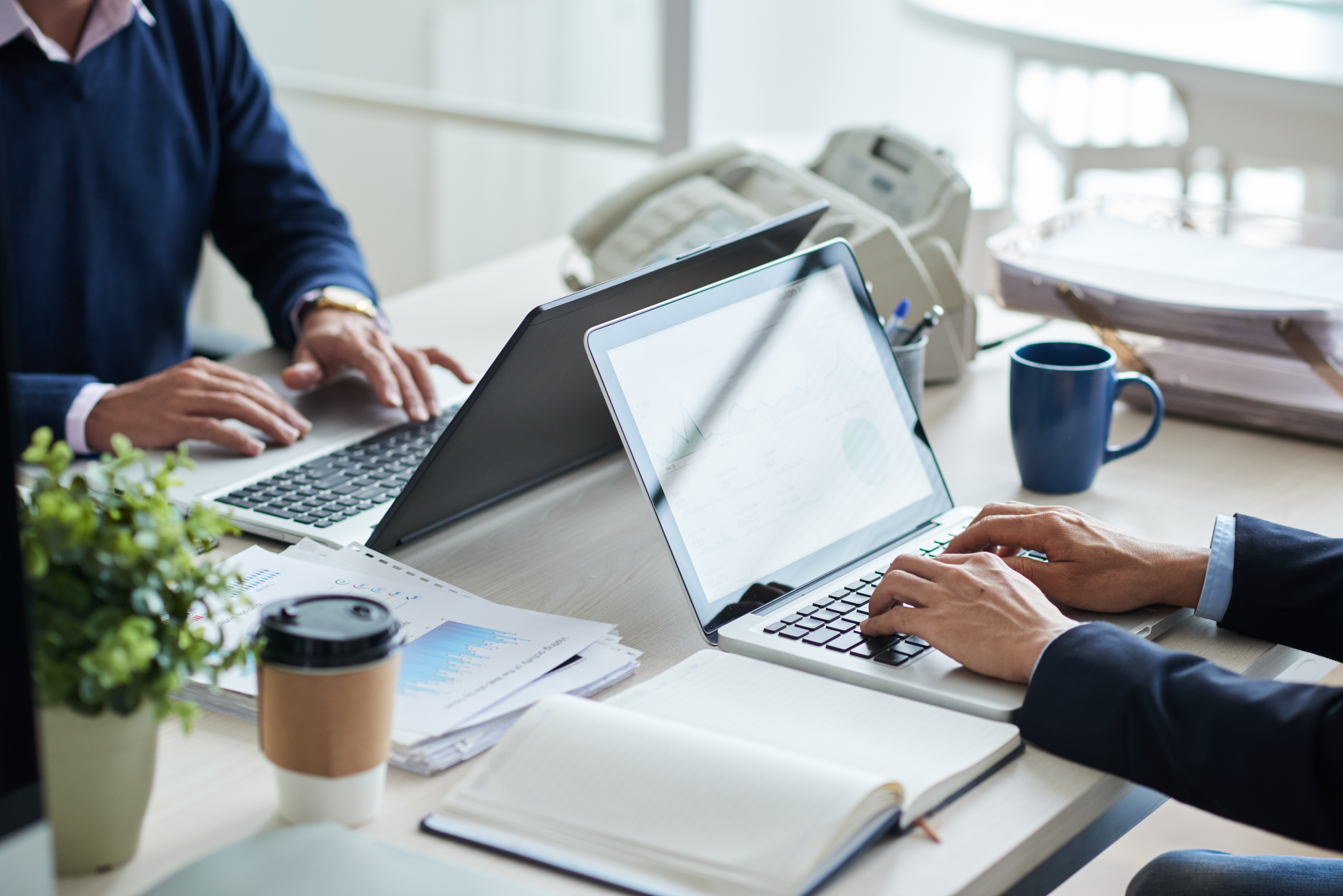 two businessmen typing on laptops